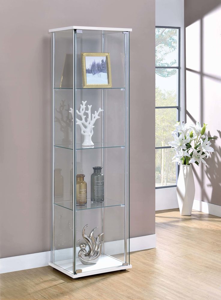 a tall glass display case with silver decorations on the top and bottom shelves, in front of a pink wall