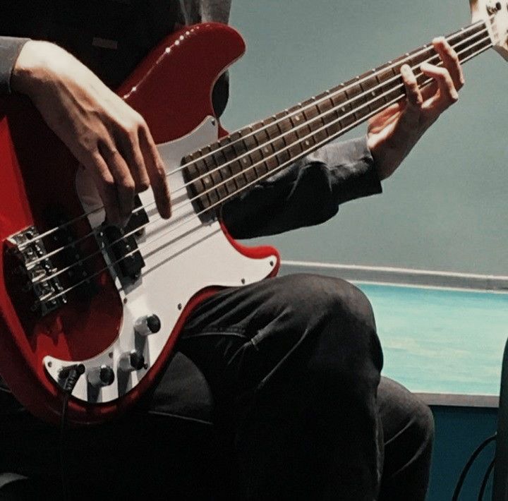 a man sitting down while playing a bass guitar