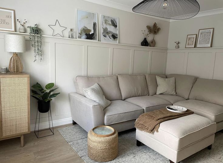 a living room with a couch, ottoman and pictures on the wall above it's headboard