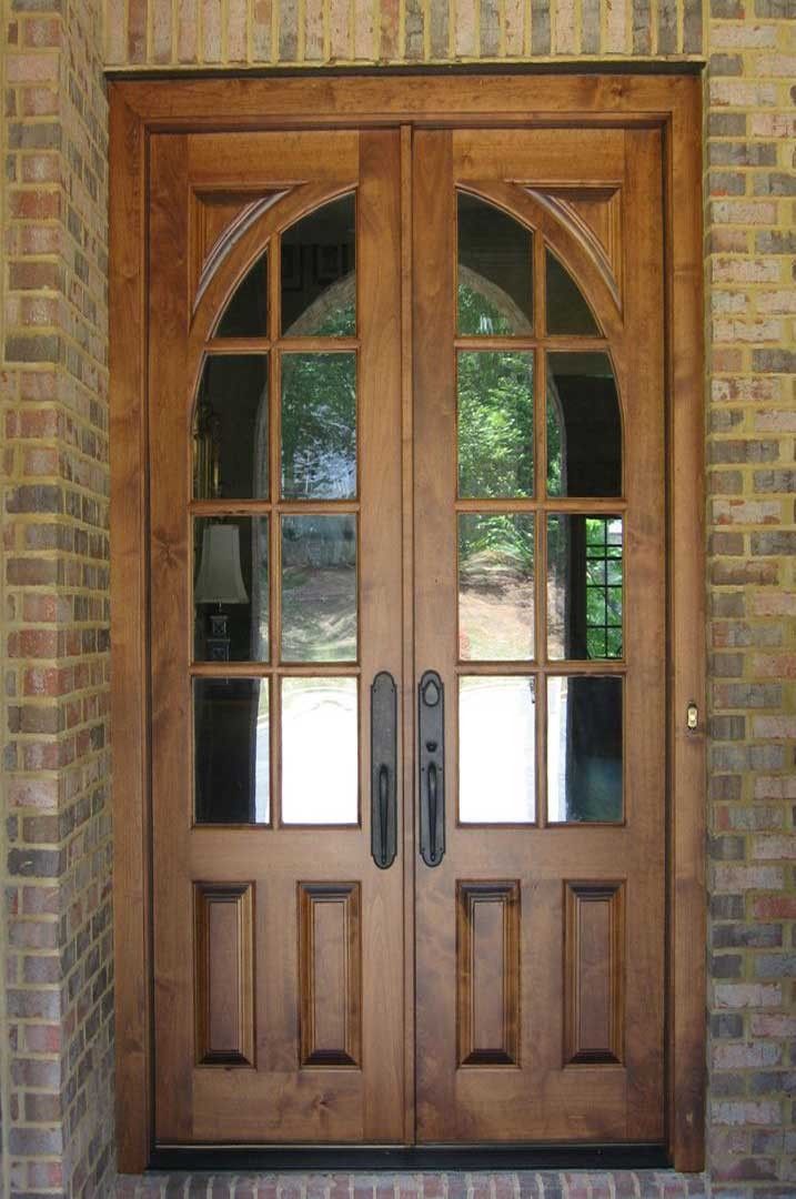 the front door is made of wood and has two glass panels on each side, along with an arched top