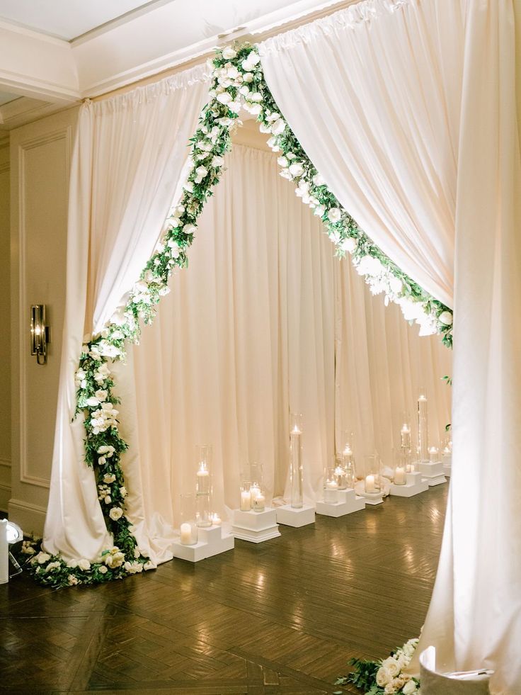 a white wedding arch decorated with flowers and candles