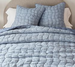 the bed is made with blue quilts and pillows