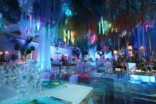 a room filled with lots of tables and chairs covered in colorful lights, hanging from the ceiling