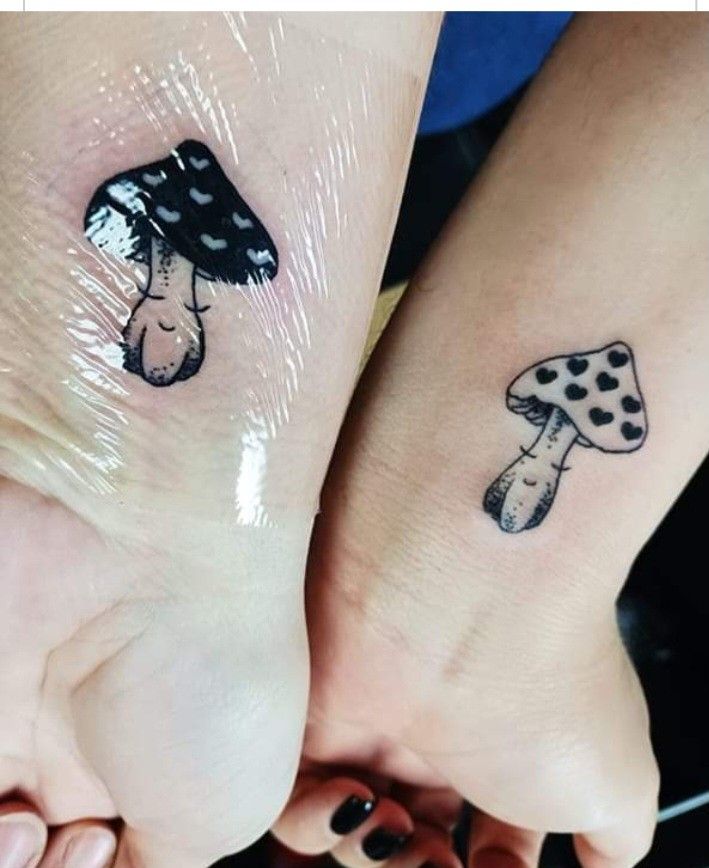 two people with matching tattoos on their feet, one is holding the other's hand