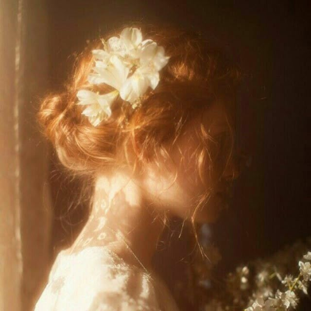 a woman with flowers in her hair is looking into the distance while wearing a white dress