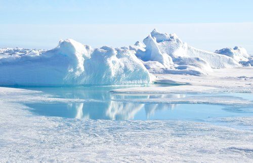 an iceberg in the middle of some water with snow on it's sides