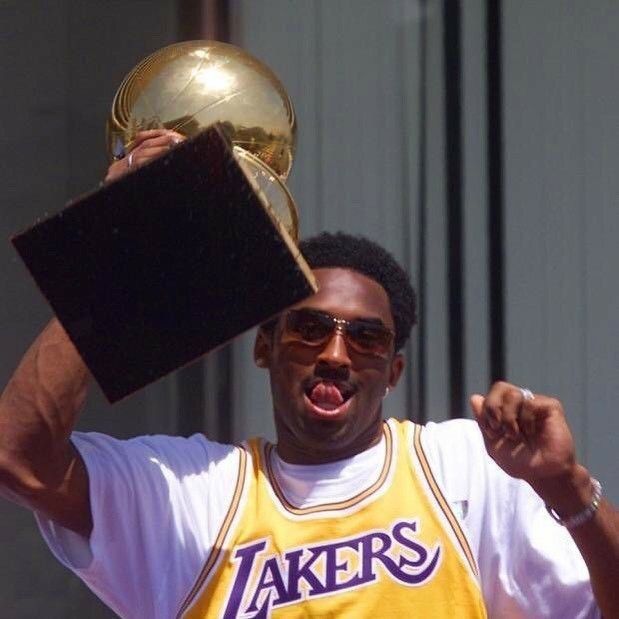 a man holding up a trophy in his right hand and wearing sunglasses on top of his head