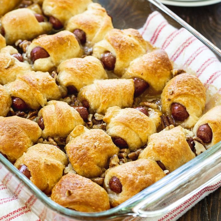 a casserole dish filled with hot dogs and other baked goods on a table