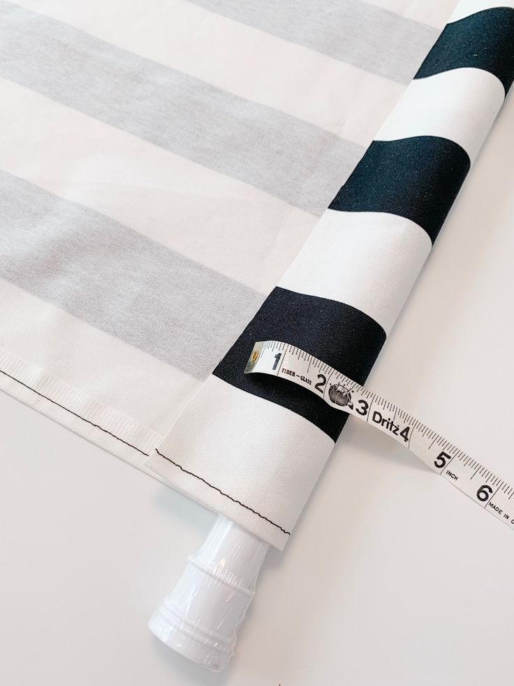 a measuring tape is on top of a black and white striped tablecloth that has been folded over