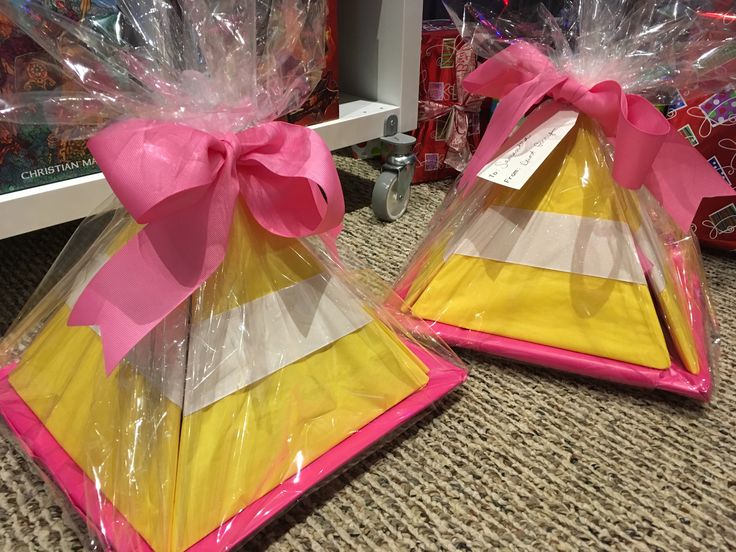 two plastic bags with bows on them sitting next to each other in front of a shelf