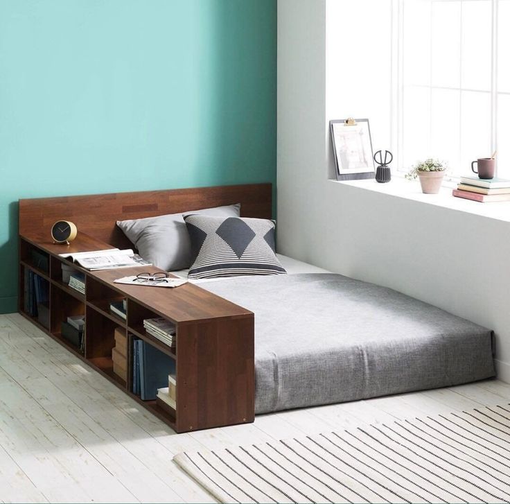 a bed sitting in the middle of a room next to a window with bookshelves