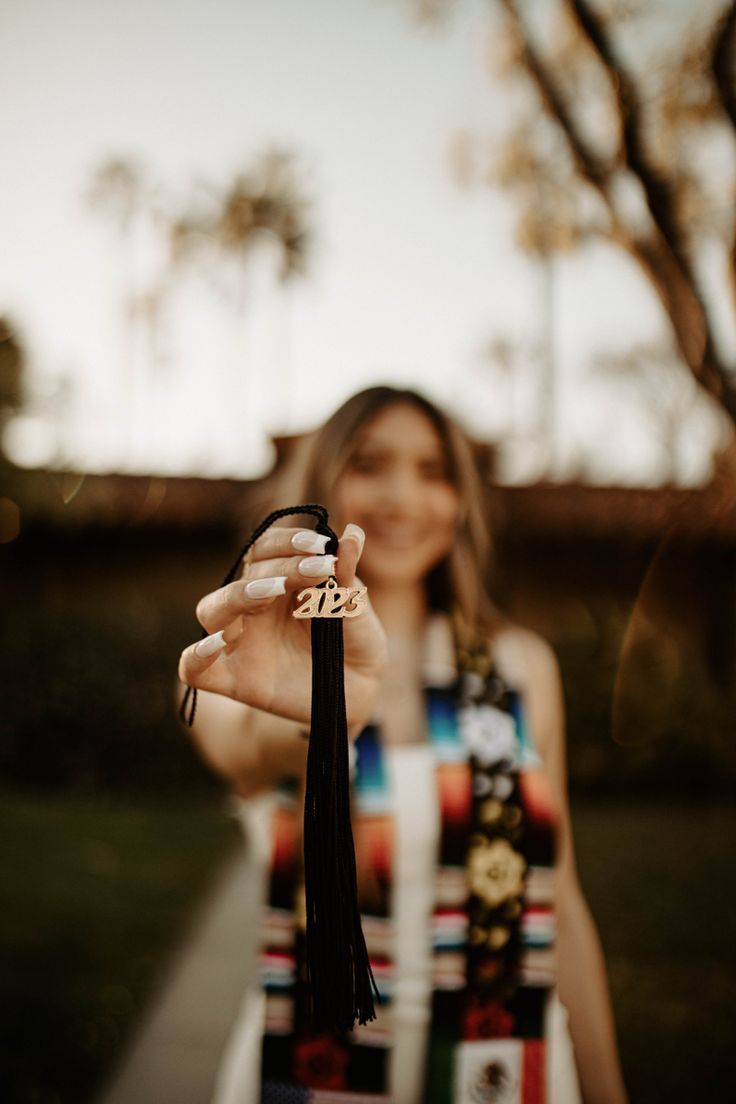 a woman is holding up her hand with the number thirteen on it and wearing a tassel