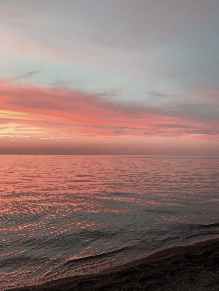 the sun is setting over the ocean with pink clouds