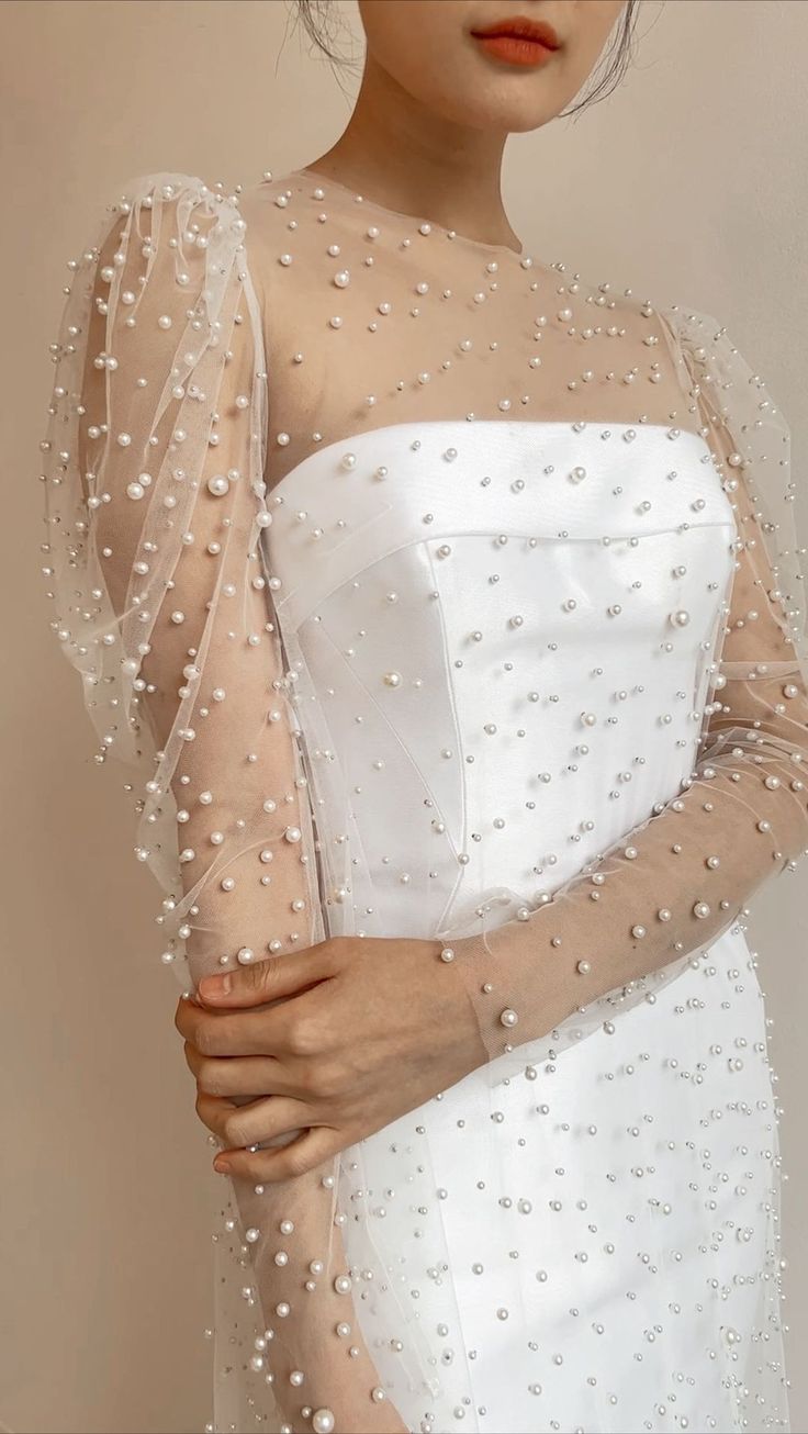 a woman in a white dress with pearls on her arm and veil over her head