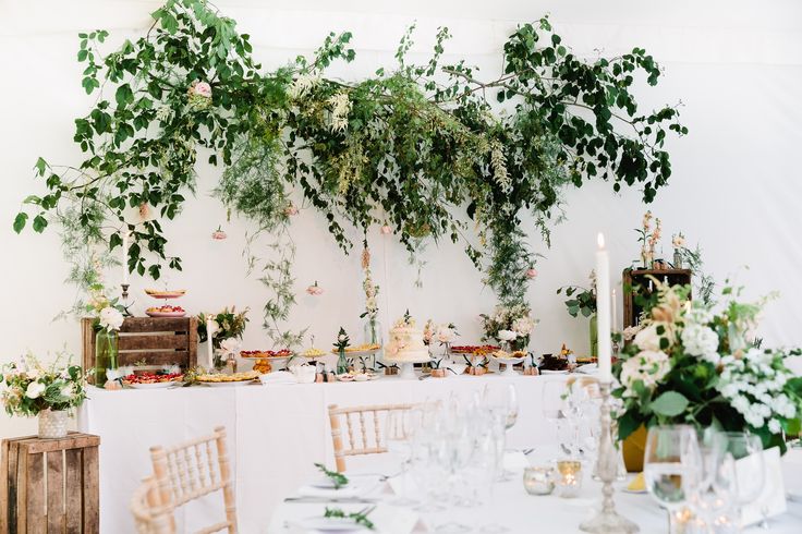 the table is set with white linens and greenery