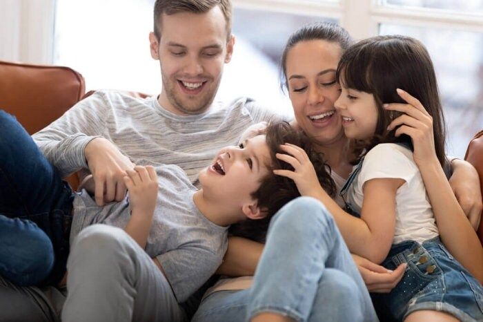 a group of young people sitting on top of a couch next to each other smiling