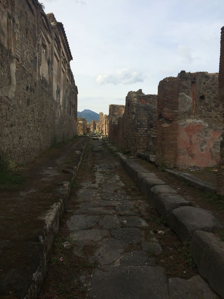 an old street with stone buildings and cobblestone roads in the distance, surrounded by grass