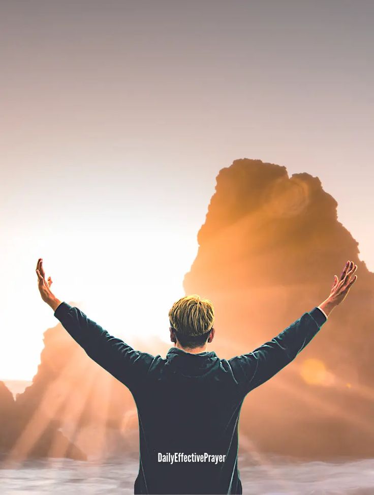 a man standing in front of a mountain with his hands up and arms wide open