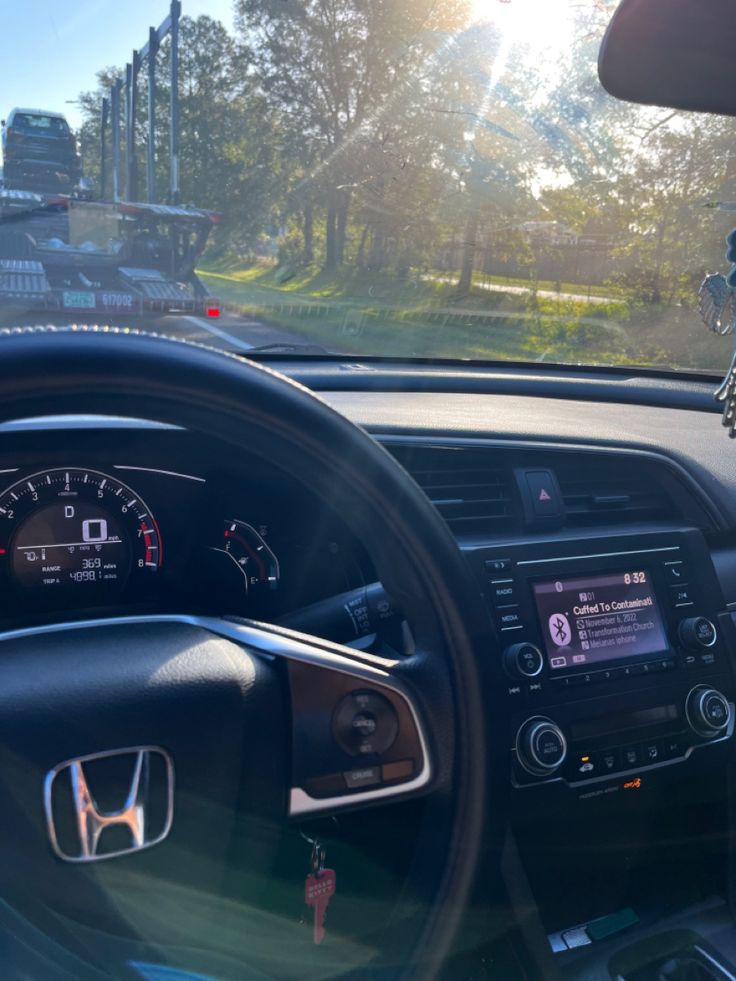 the interior of a car with an electronic display and steering wheel controls in front of it