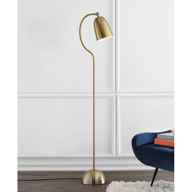 a gold floor lamp with a white rug and blue chair next to it in front of a wall