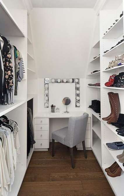 an organized closet with white shelving and lots of shoes on the shelves, along with a chair