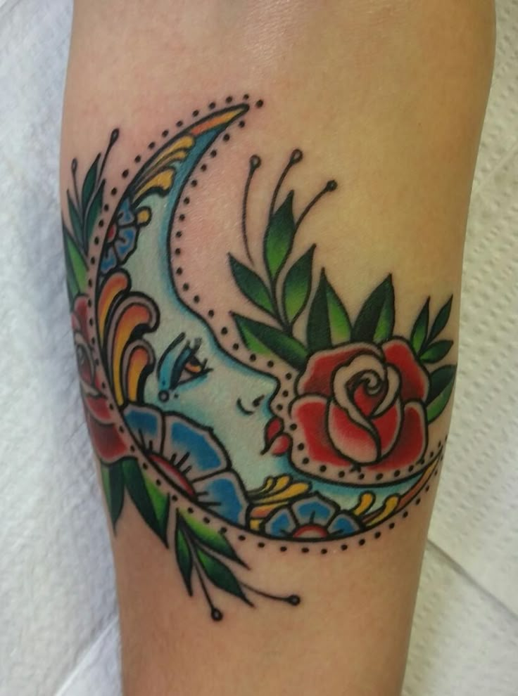 a woman's leg with a tattoo on it that has a crescent and roses on it