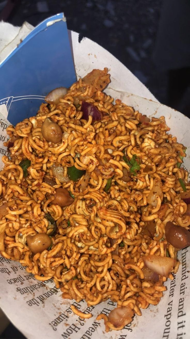 a pile of noodles sitting on top of a white paper plate covered in meat and veggies