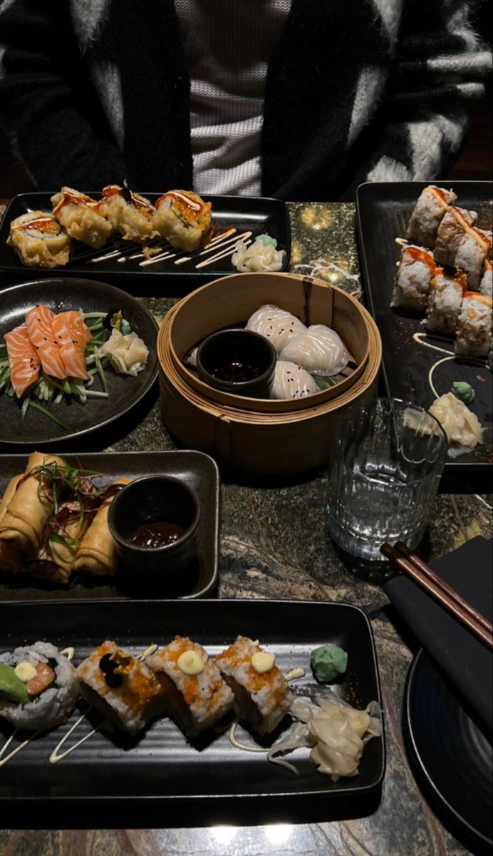 a table topped with black trays filled with sushi