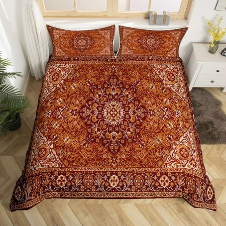 a bed with an orange and red bedspread on top of wooden flooring