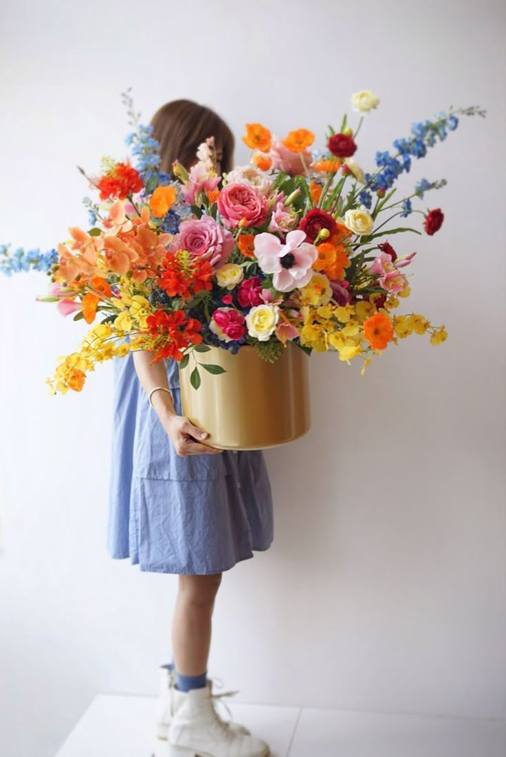 a woman holding a bucket full of colorful flowers