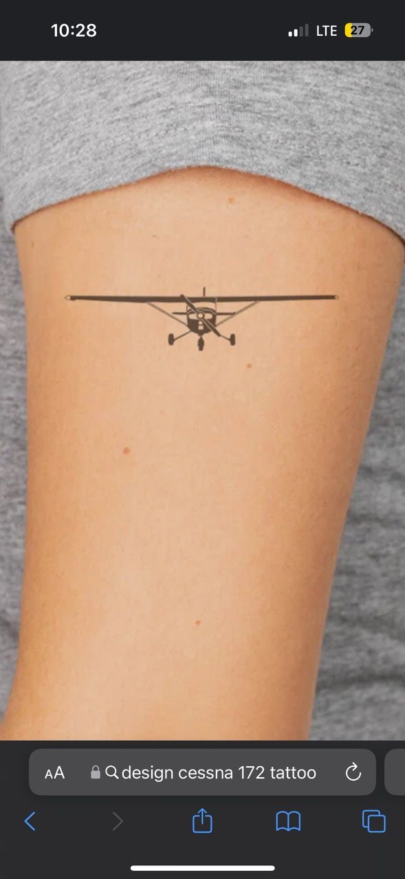 an airplane tattoo on the back of a woman's thigh, with text below it