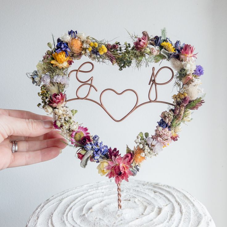 a heart shaped cake topper with flowers in the shape of a love sign on it