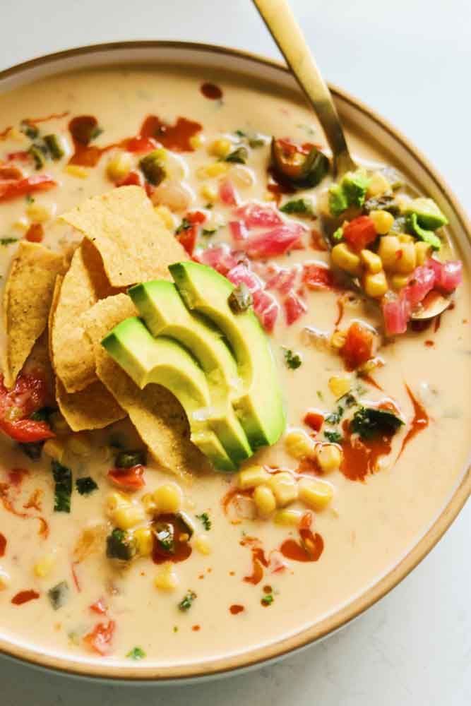 a bowl filled with corn, avocado and tortilla chips