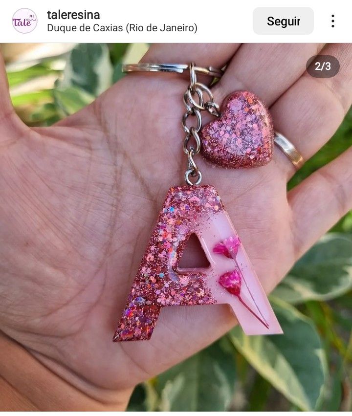 a hand holding two pink letters with glitter on them in the shape of a heart