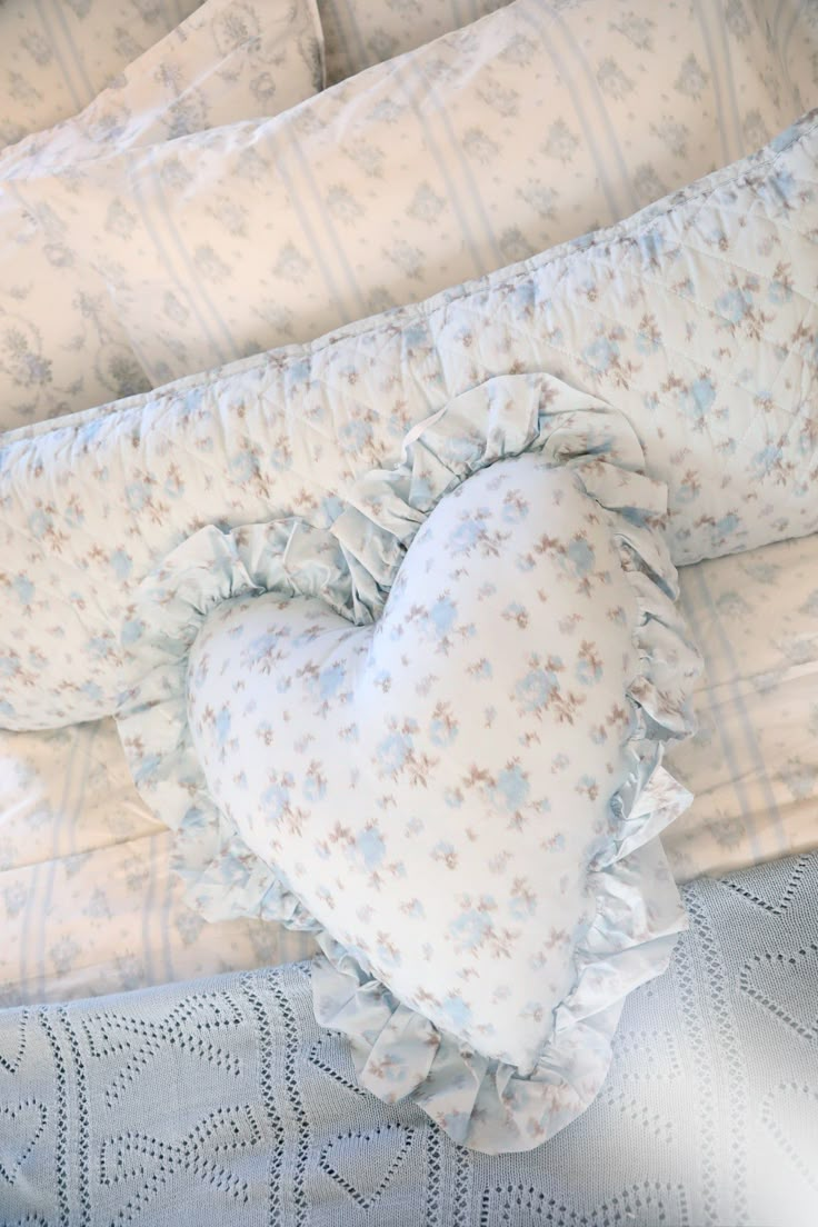 a heart shaped pillow sitting on top of a bed