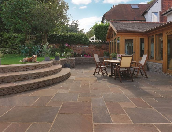 an outdoor patio with steps leading to the back door and dining table in the foreground