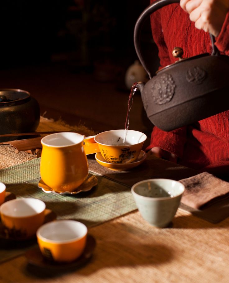 a person pouring tea into cups on a table