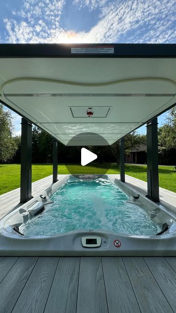 a hot tub sitting on top of a wooden deck next to a lush green field