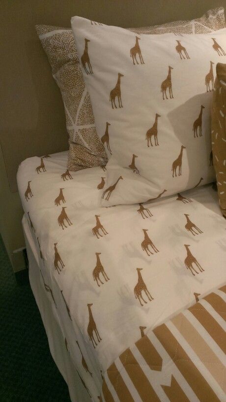 a bed with giraffes on the sheets and pillows