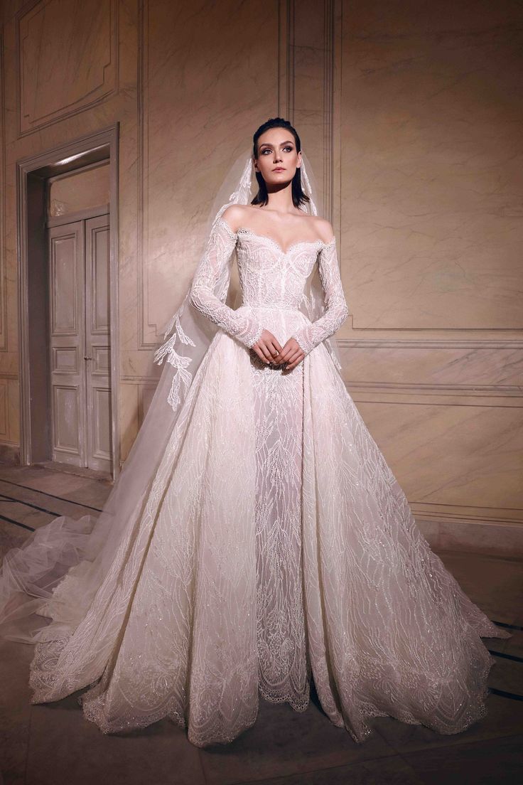 a woman in a white wedding gown with long sleeves and a veil on her head