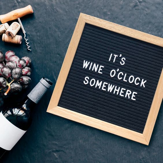 a sign that says it's wine o'clock somewhere next to some bottles and corks