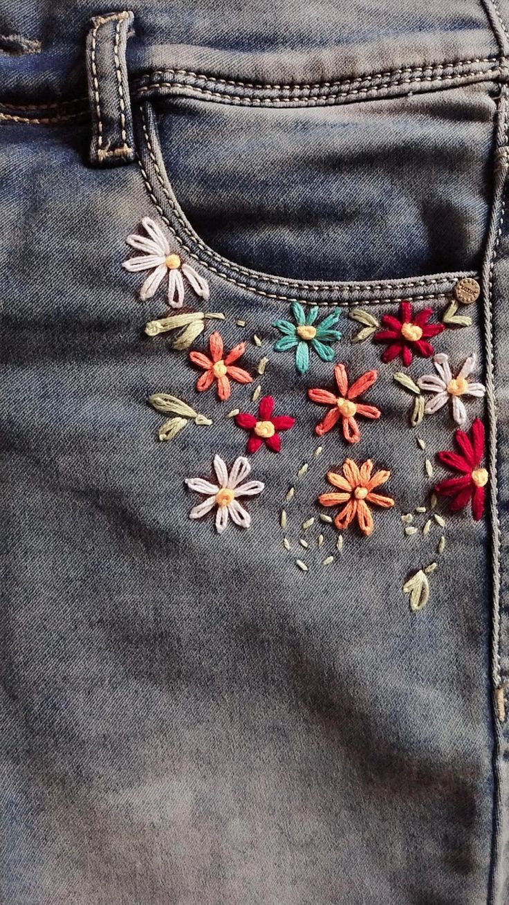 a pair of jeans with embroidered flowers on them