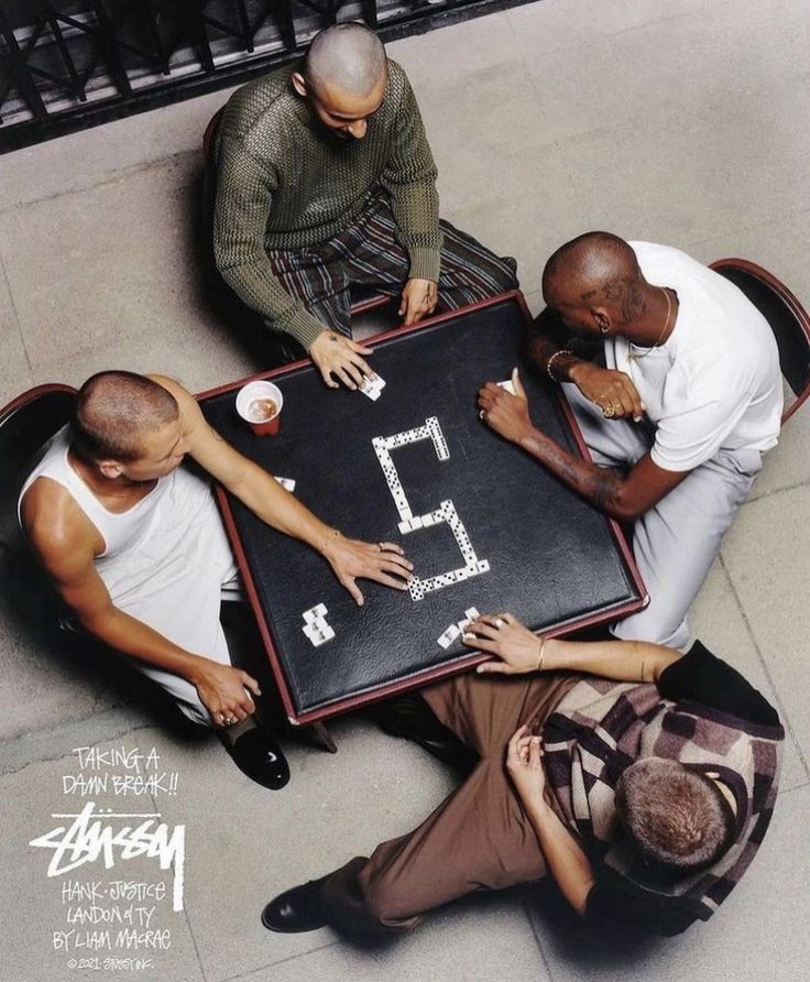 four men sitting at a table playing a game with the number five written on it