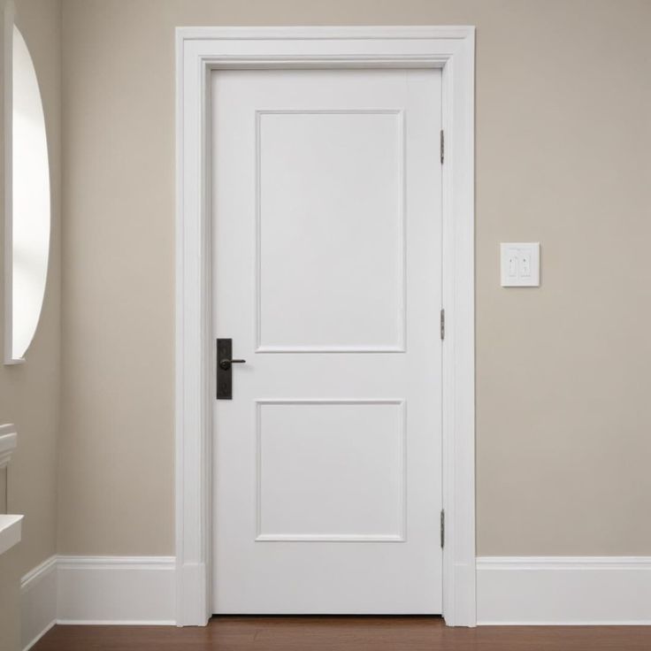 an empty room with a white door and wooden floor