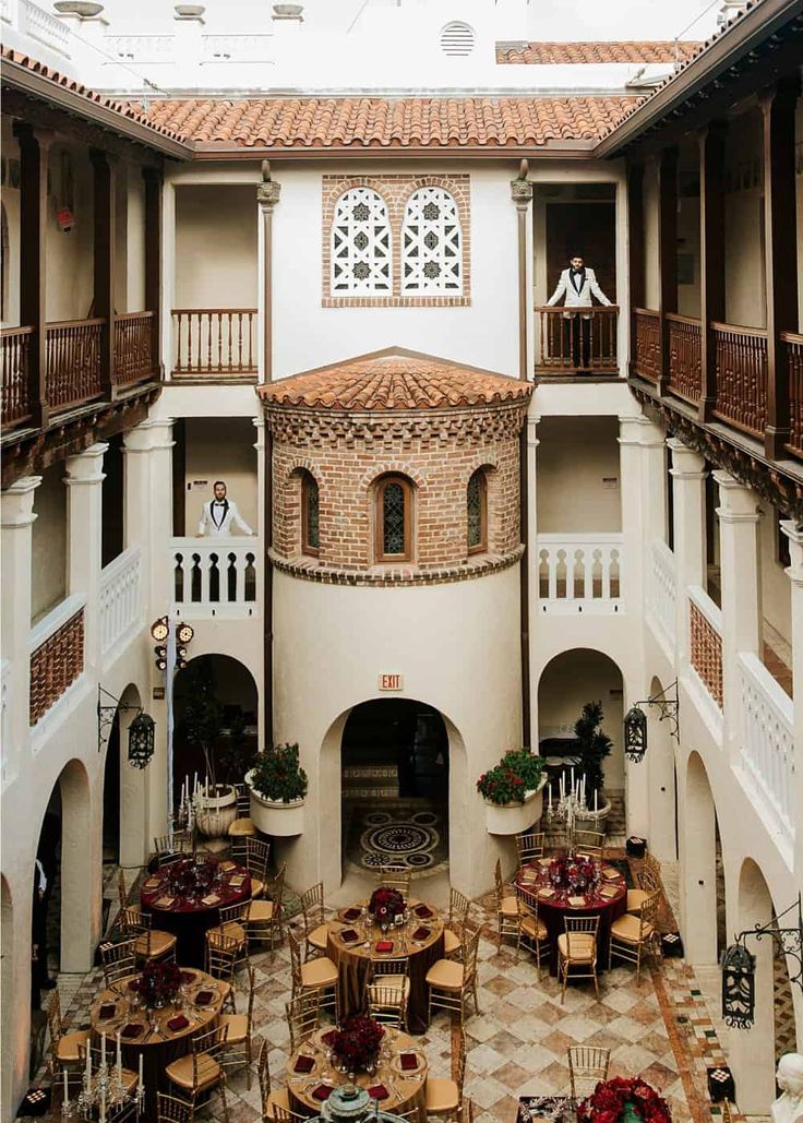 an indoor dining area with tables and chairs in the center, surrounded by two balconies