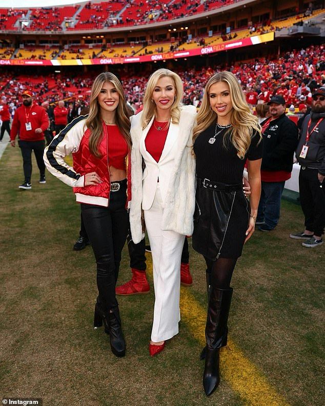 two women standing next to each other in front of a crowd at a football game