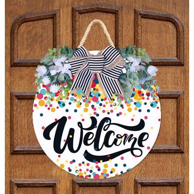 a welcome sign hanging on a door with polka dotes and ribbon attached to it