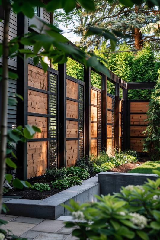 an outdoor garden with lots of plants and wooden fenced in areas that are surrounded by greenery