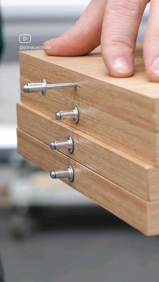 a person's hand is on top of a wooden box with three screws