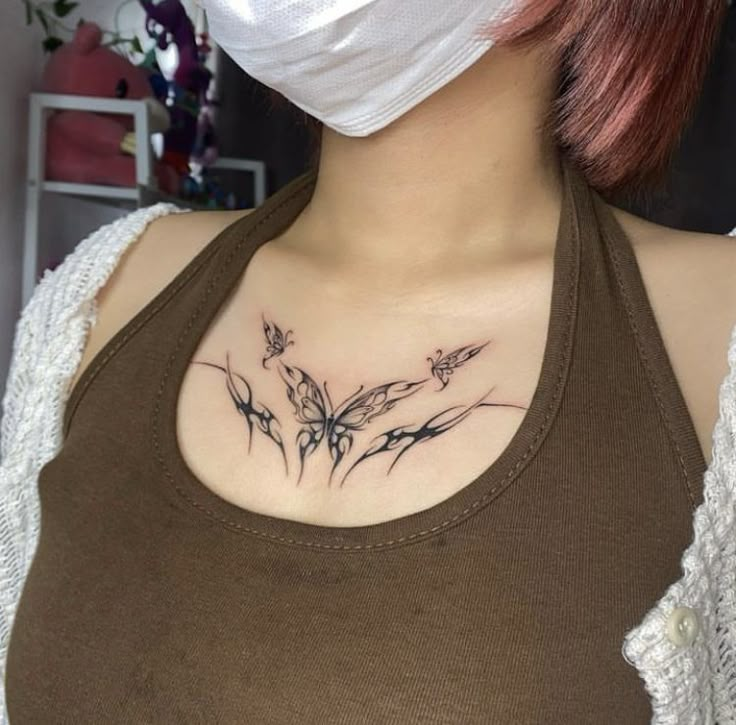 a woman wearing a face mask with tattoos on her chest and behind her is a flower